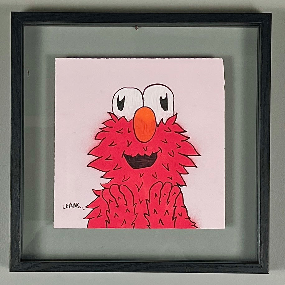 Framed artwork of a red character with a large orange nose on a light pink background.