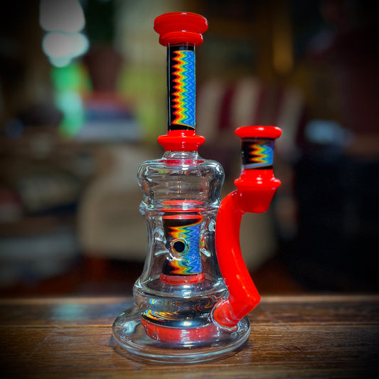 A multicolored glass piece with red accents and rainbow line work, featuring a 9-slit perc and a 14mm joint.