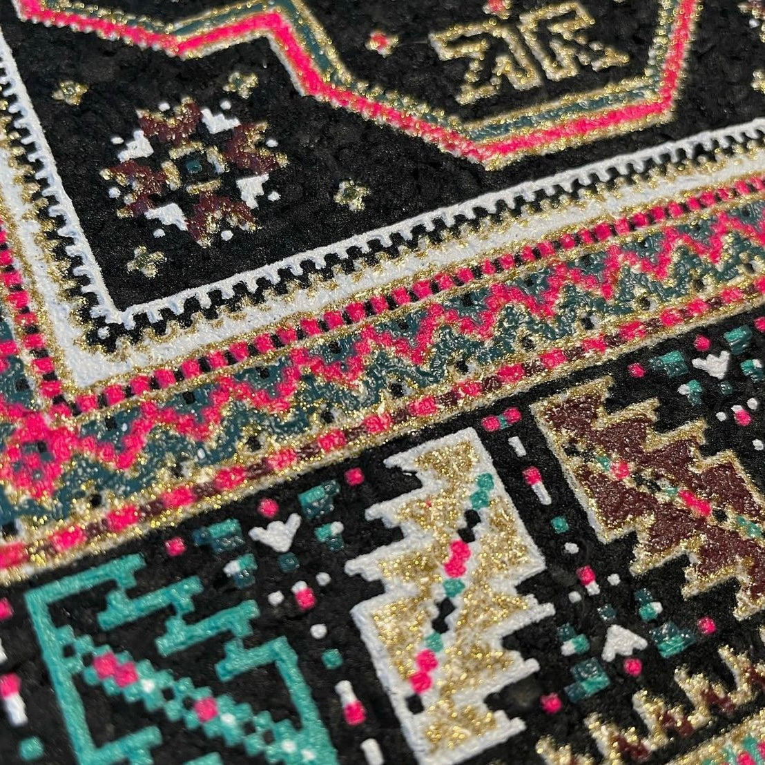 A rectangular 'High Roller Bitrug' mood mat with a geometric pattern featuring a central pink and black design, created with upcycled scraps.