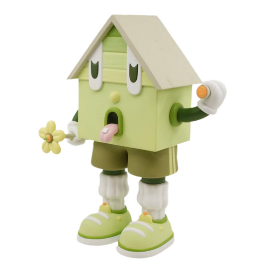 A toy figure of a character resembling a house with eyes, wearing green shorts, a green and white shirt, and green and white shoes, holding a yellow flower.