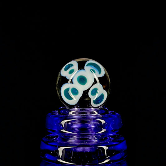 A multicolored glass marble with a design resembling a flower with blue petals on a white background, with a diameter approximately of 22mm.