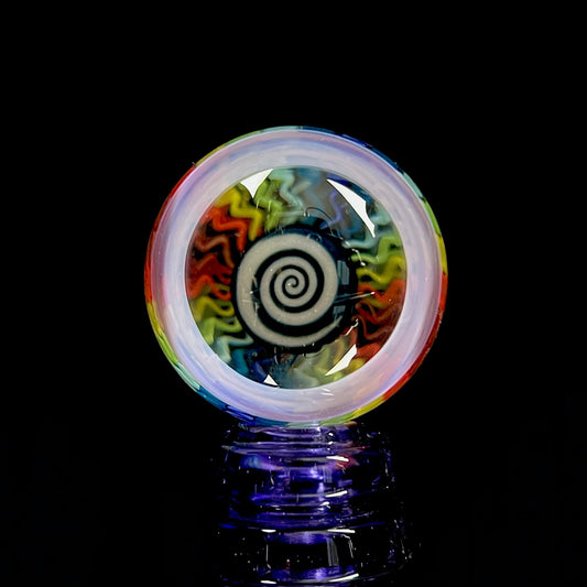 A multicolored spiral pattern marble with a predominantly black center and radiating swirls of blue, red, and green.