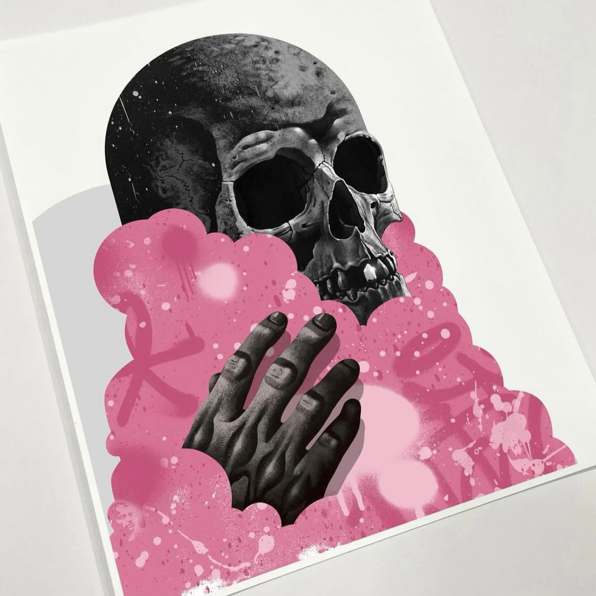 Art print with a skull and praying hands surrounded by pink smoke on a white background.