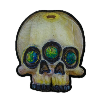 A mood mat with a skull design featuring a third eye in the center, with a multicolored, glowing appearance.