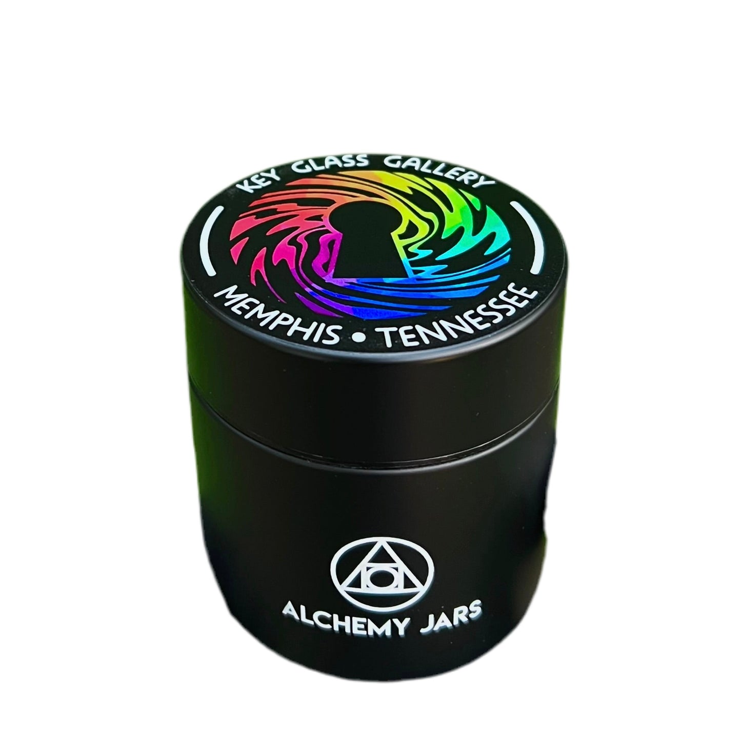 A black glass jar with a colorful geometric pattern design on the lid, labeled 'ALCHEMY JARS' and 'Memphis, Tennessee - Key Glass Gallery'.