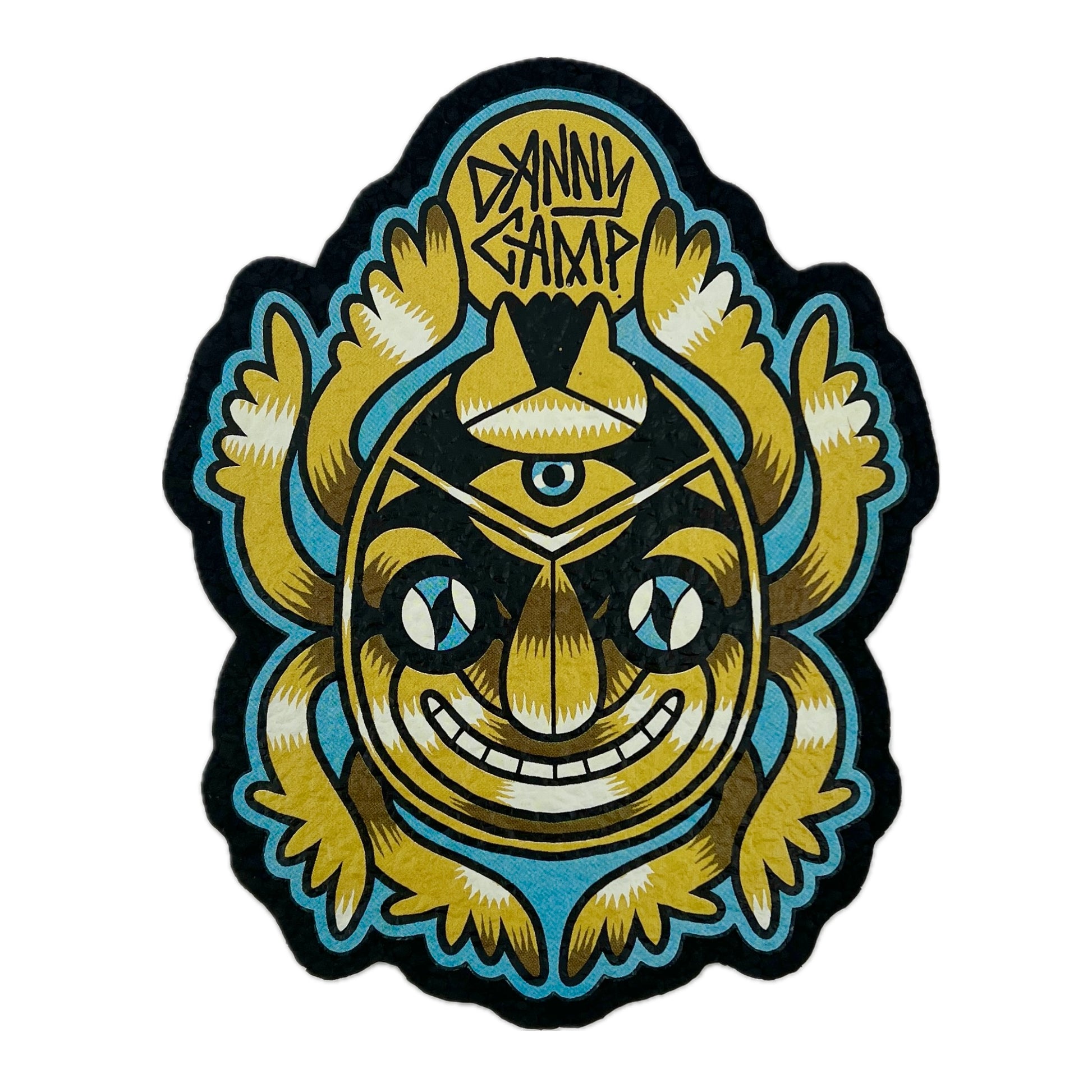 A rectangular moodmat with a design featuring a stylized face with eyes and teeth, predominantly in gold and blue colors with the text 'DANNY CAMP' at the top.