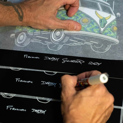 Person signing a print of a car illustration with a pen.