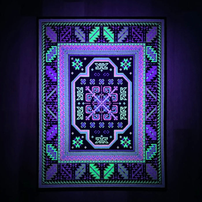 A rectangular rug with a geometric pattern featuring a central blue and purple abstract design, surrounded by a black border with additional geometric patterns in green and yellow.