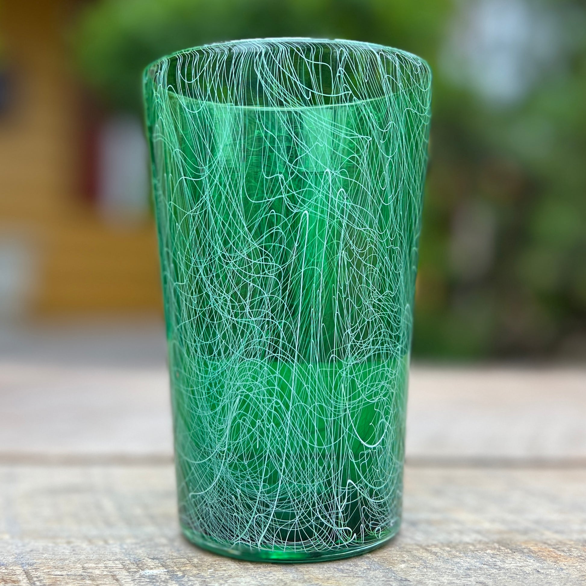 A green glass pint with unique patterns and a semi-transparent appearance.