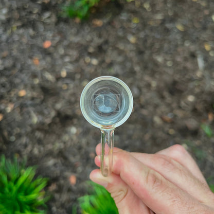 Hand holding a small quartz bucket with a blurred natural background.