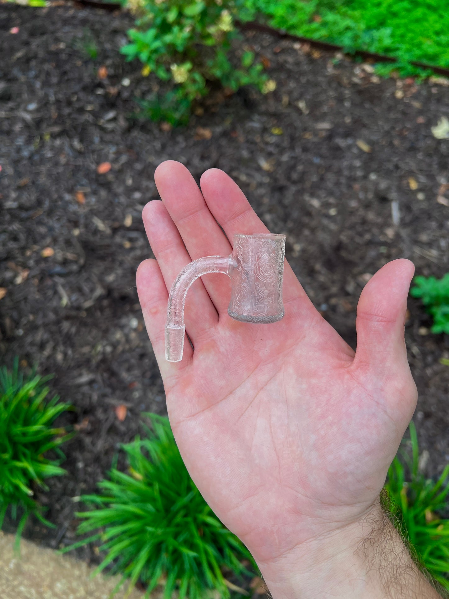 Sandblasted quartz bucket held in a hand with a garden background
