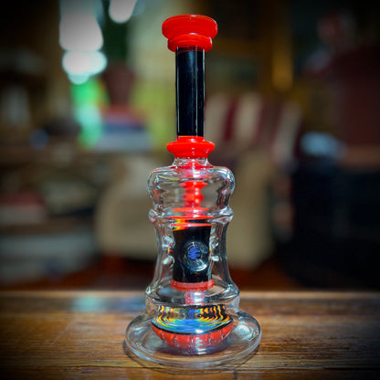 A multicolored glass piece with red accents and rainbow line work, featuring a 9-slit perc and a 14mm joint.