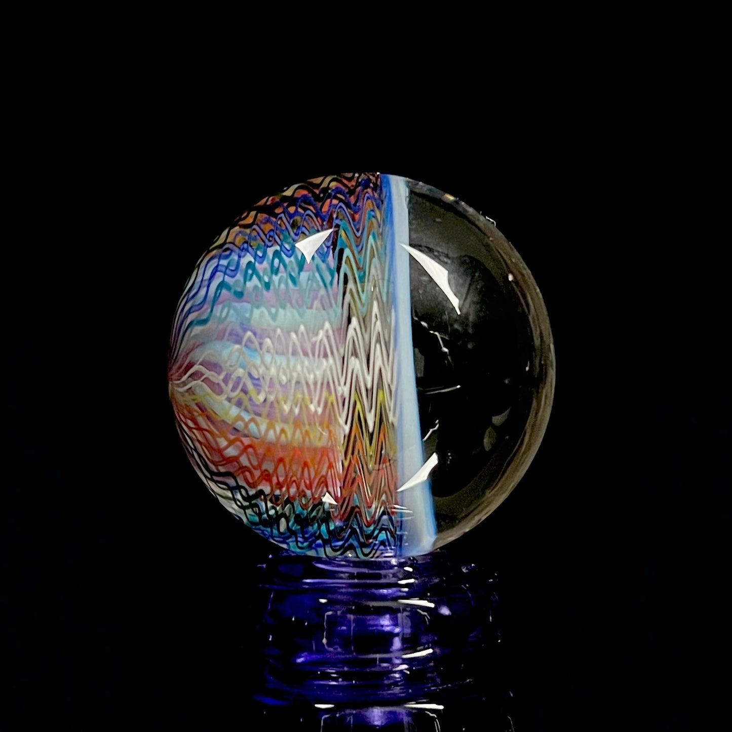 A multicolored glass marble with a swirl pattern, approximately 38mm in diameter.