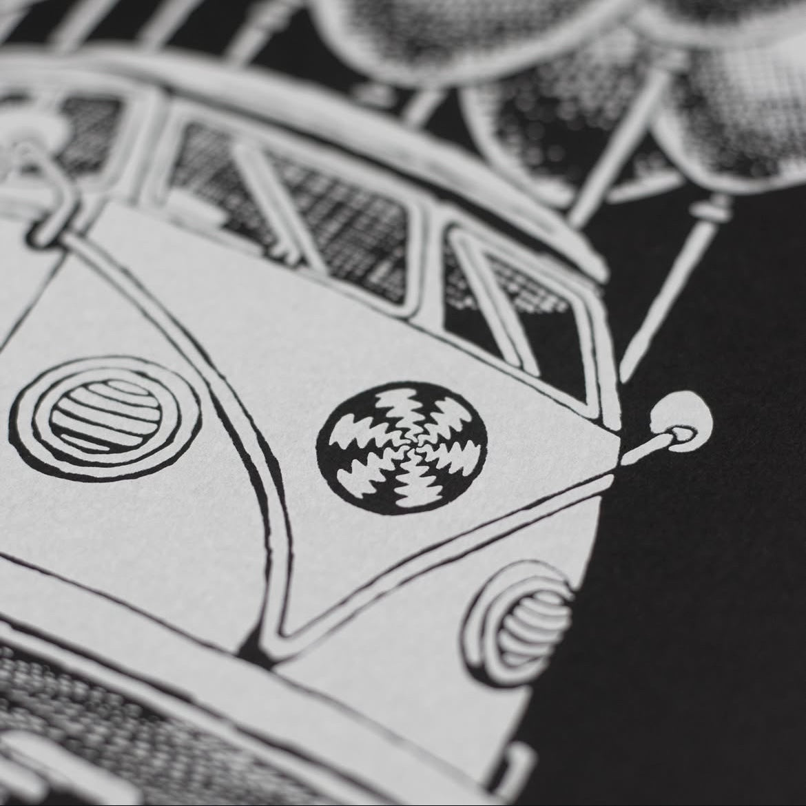 Close-up of a hand screen printed white ink on black paper, depicting a stylized bus.
