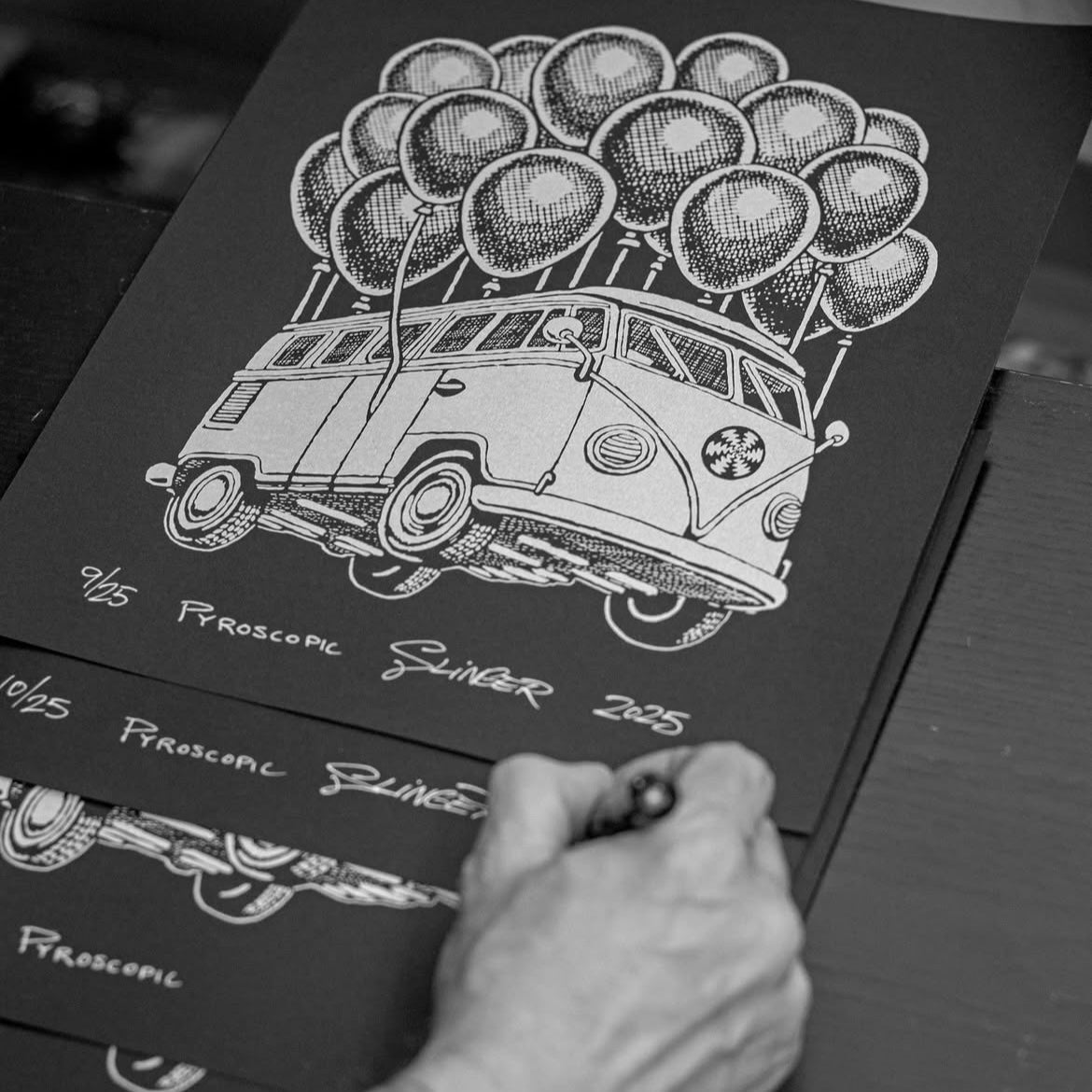 Black and white illustration of a vintage van with balloons on a dark surface.