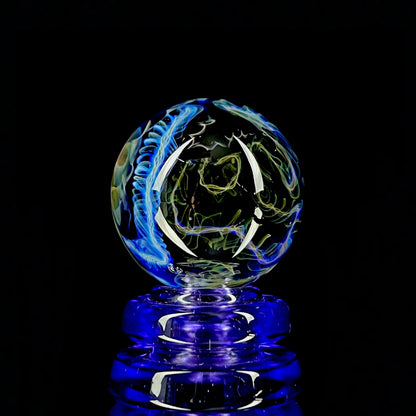A colorful glass marble with a design featuring blue and yellow, crafted by Phase Glass.