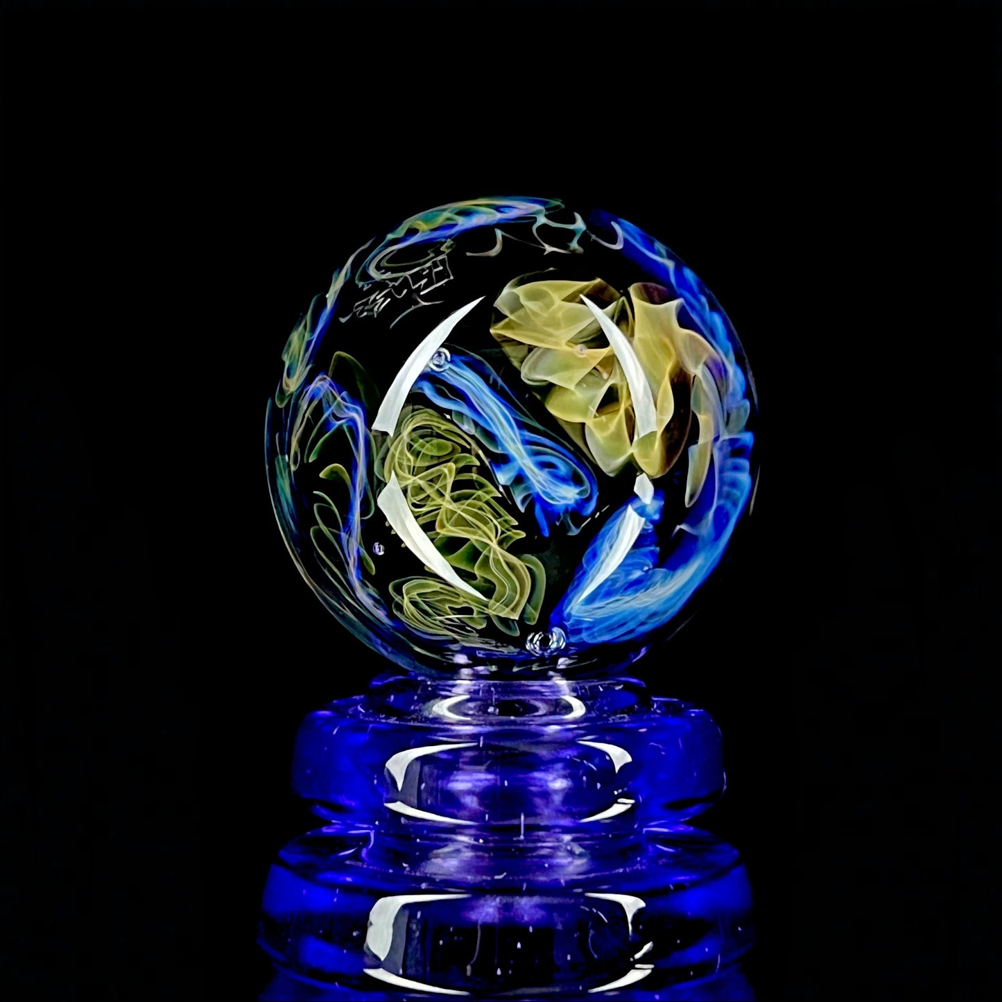 A colorful glass marble with a design featuring blue and yellow, crafted by Phase Glass.