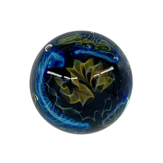 A glass marble with a predominantly blue color and green accents, featuring intricate patterns.