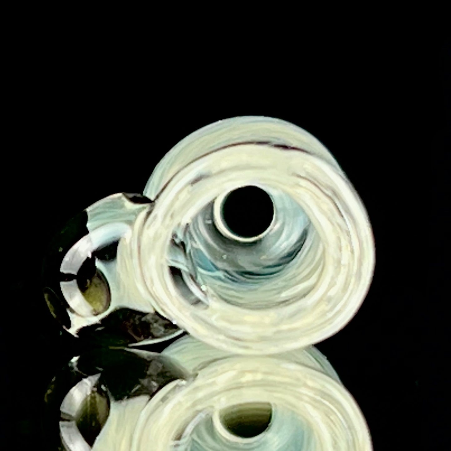 A glass fume tip with swirls of color, primarily clear with blue patterns, designed for use with larger rolls.