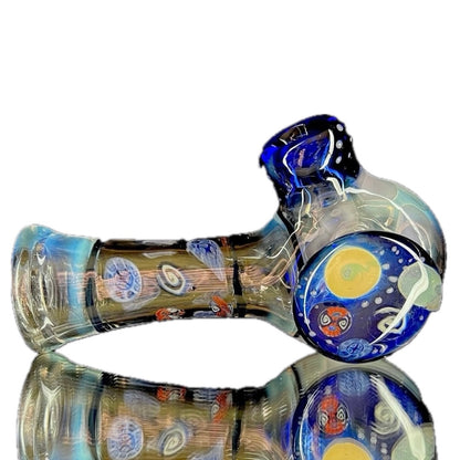 A glass hand pipe with a space-themed design, featuring a small bowl, lip wraps, and a donut shape under the bowl.