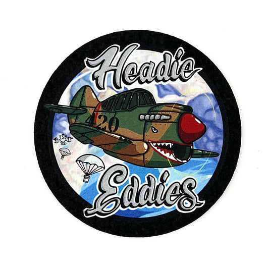 A round mood mat with an illustration of a cartoon-style airplane named 'Headie Eddie's' dropping bombs.