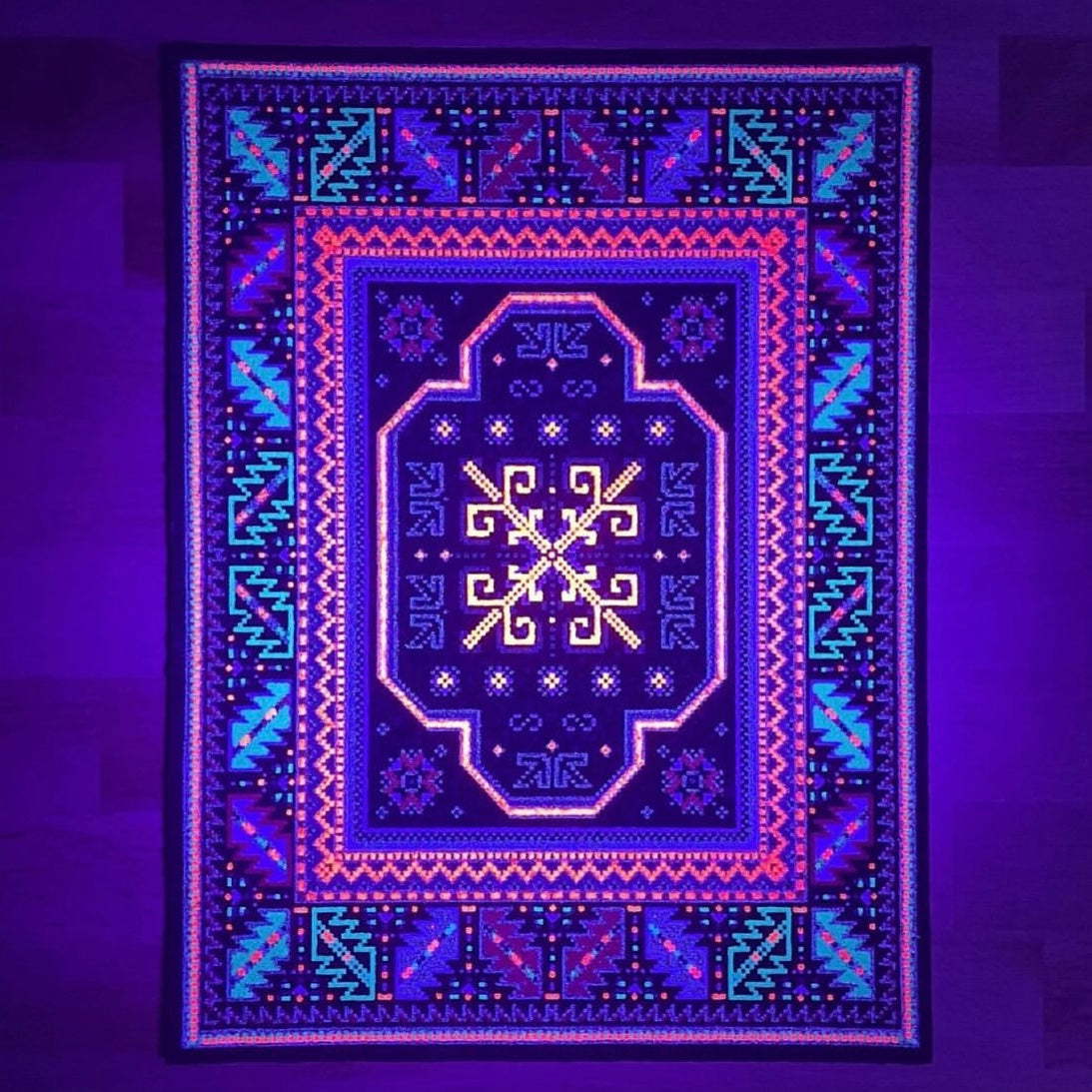 A rectangular 'High Roller Bitrug' mood mat with a geometric pattern featuring a central pink and black design, created with upcycled scraps.