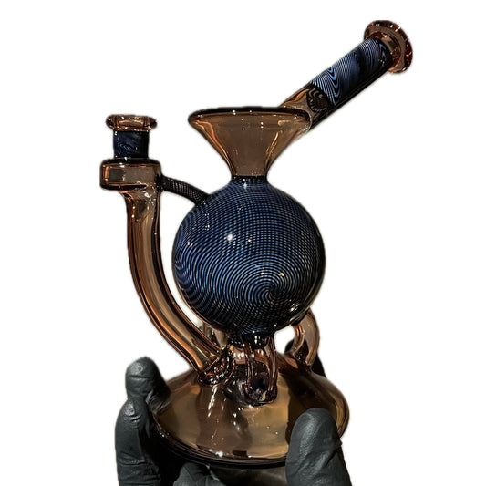 A hand holding a tall, multicolored glass piece with a 12-hole circle perc and a marble.