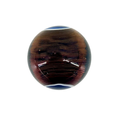 Round glass paperweight with brown and blue pattern on a white background.
