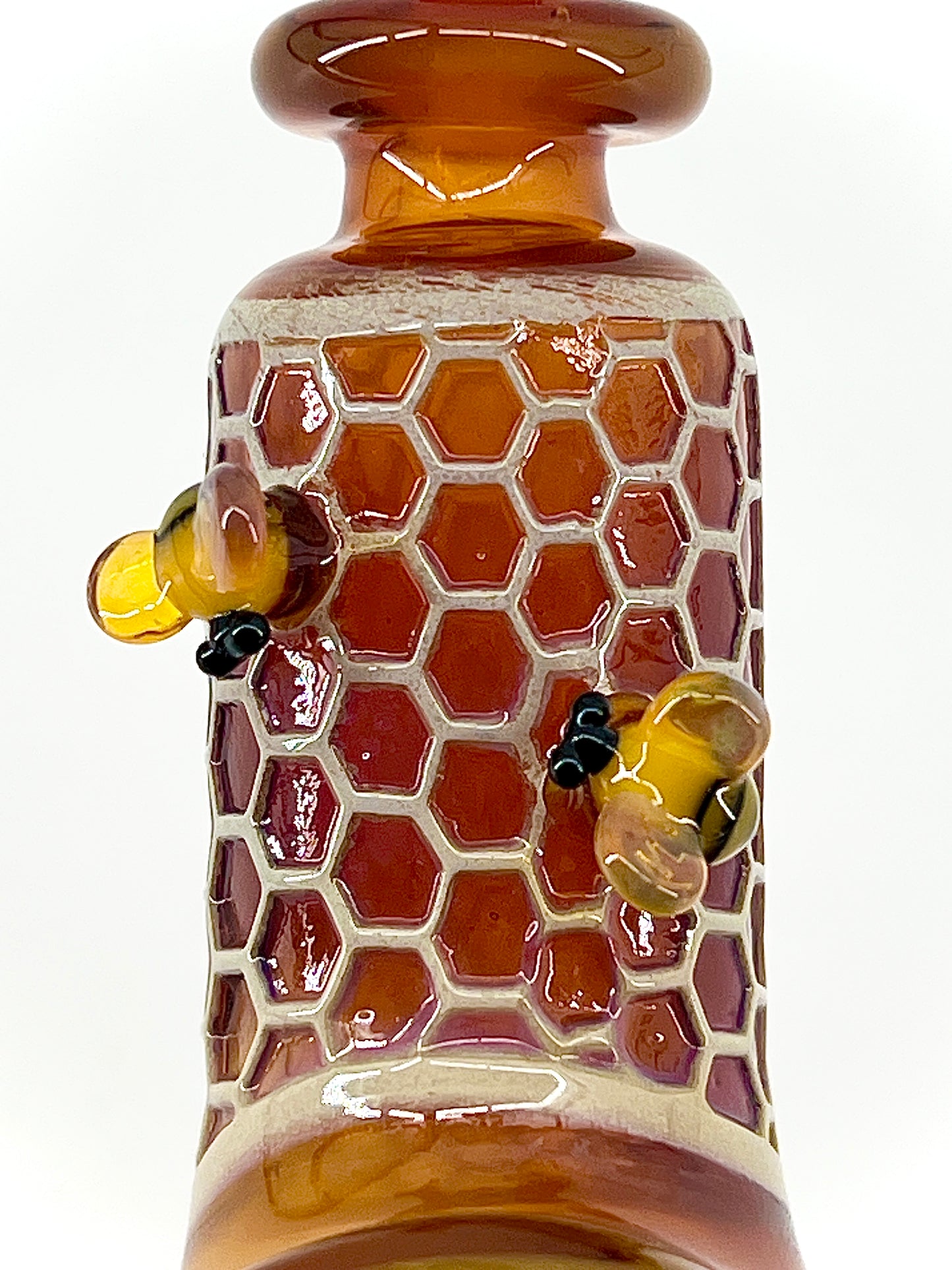 Glass pipe with honeycomb design and bee decorations on a white background.