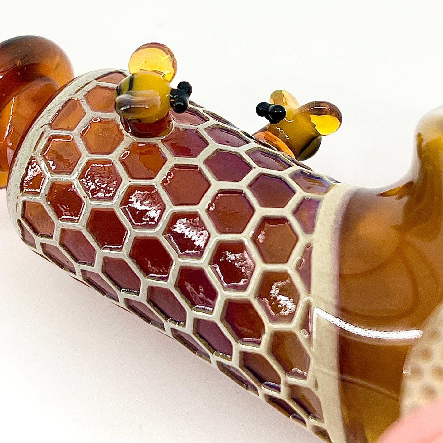 Glass pipe with honeycomb design and bee decorations on a white background.
