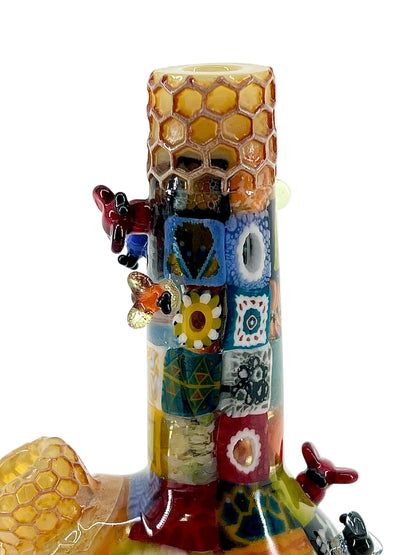 Colorful glass bee sculpture with honeycomb details on a white background.