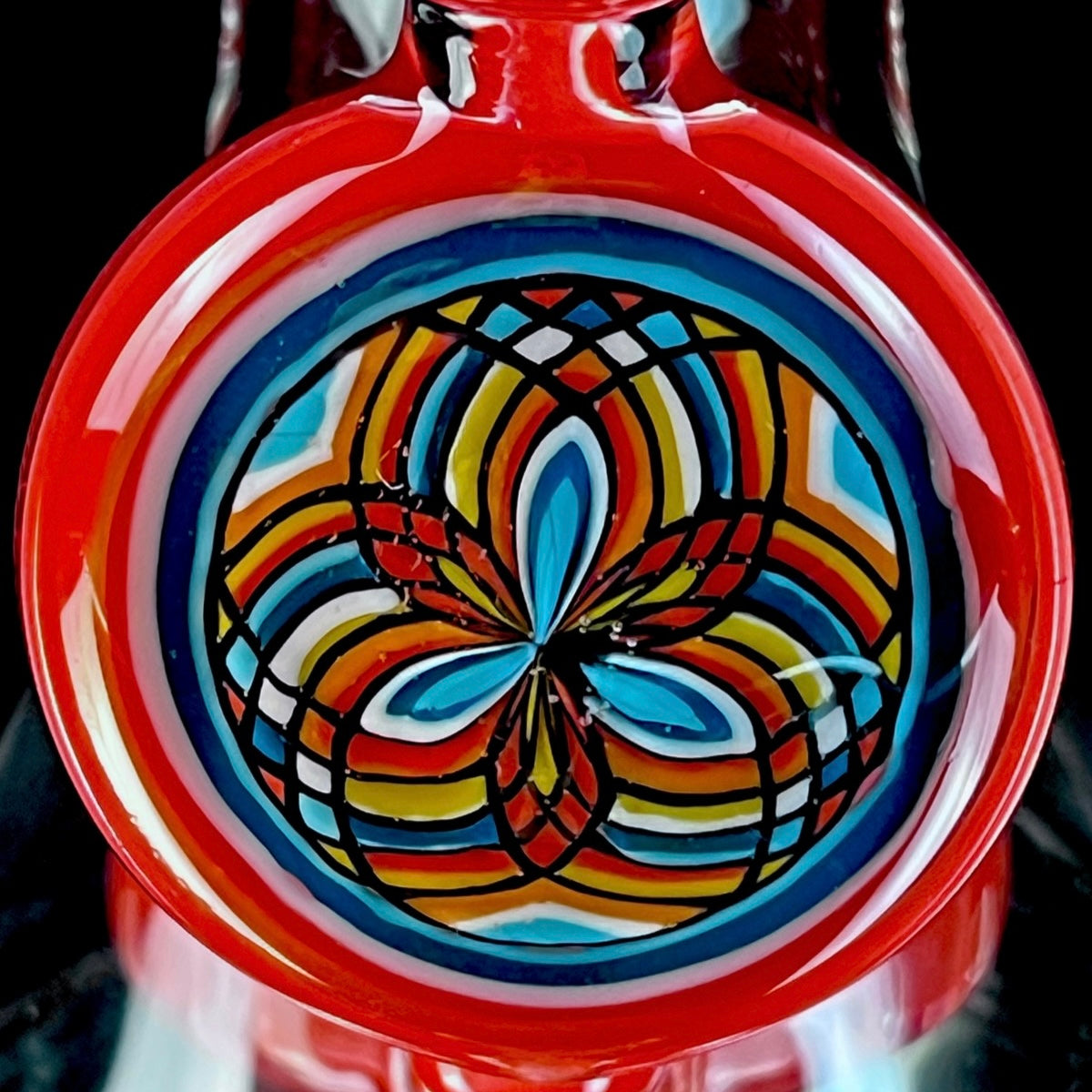 Red and clear glass smoking device with colorful designs on a white background.