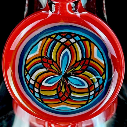 Red and clear glass smoking device with colorful designs on a white background.