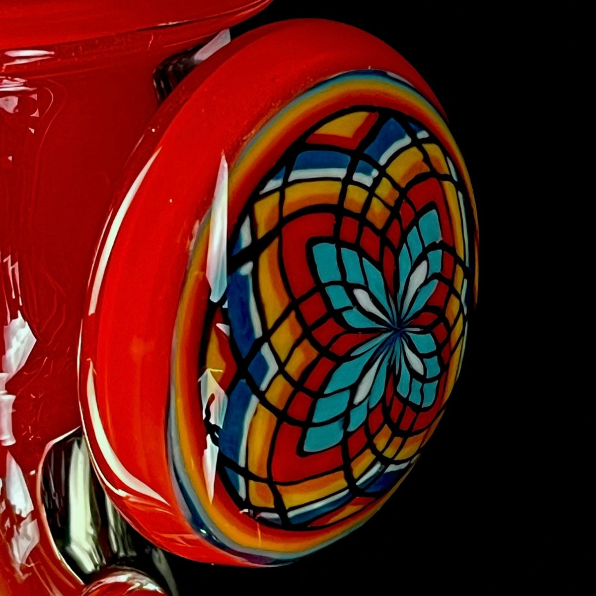 Red and clear glass smoking device with colorful designs on a white background.