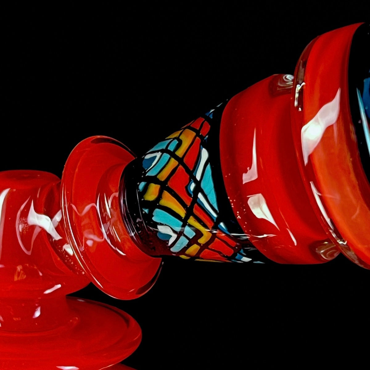 Red and clear glass smoking device with colorful designs on a white background.