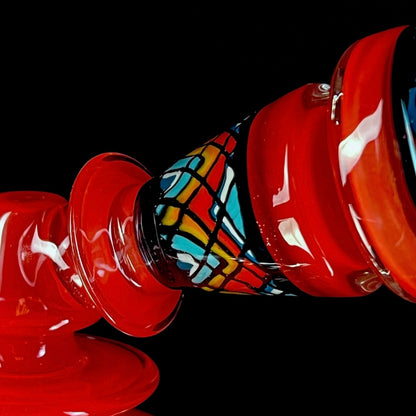 Red and clear glass smoking device with colorful designs on a white background.