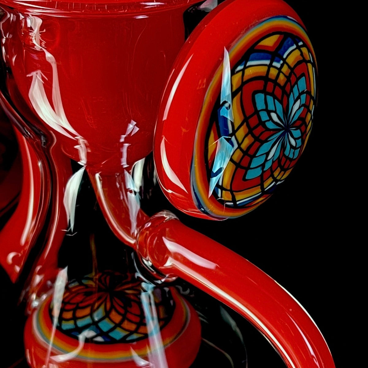 Red and clear glass smoking device with colorful designs on a white background.