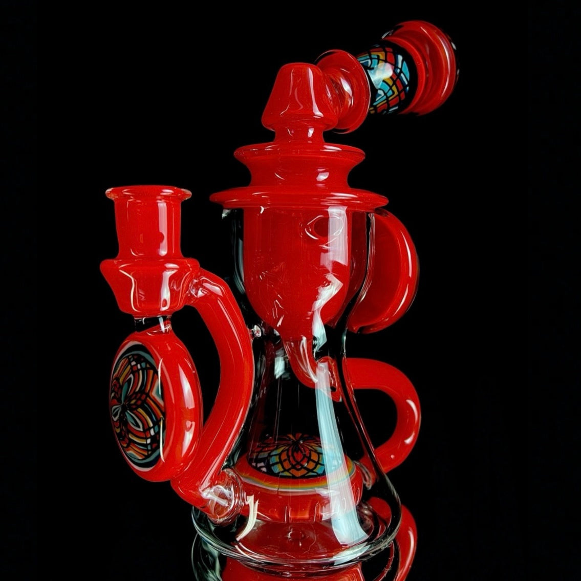 Red and clear glass smoking device with colorful designs on a white background.