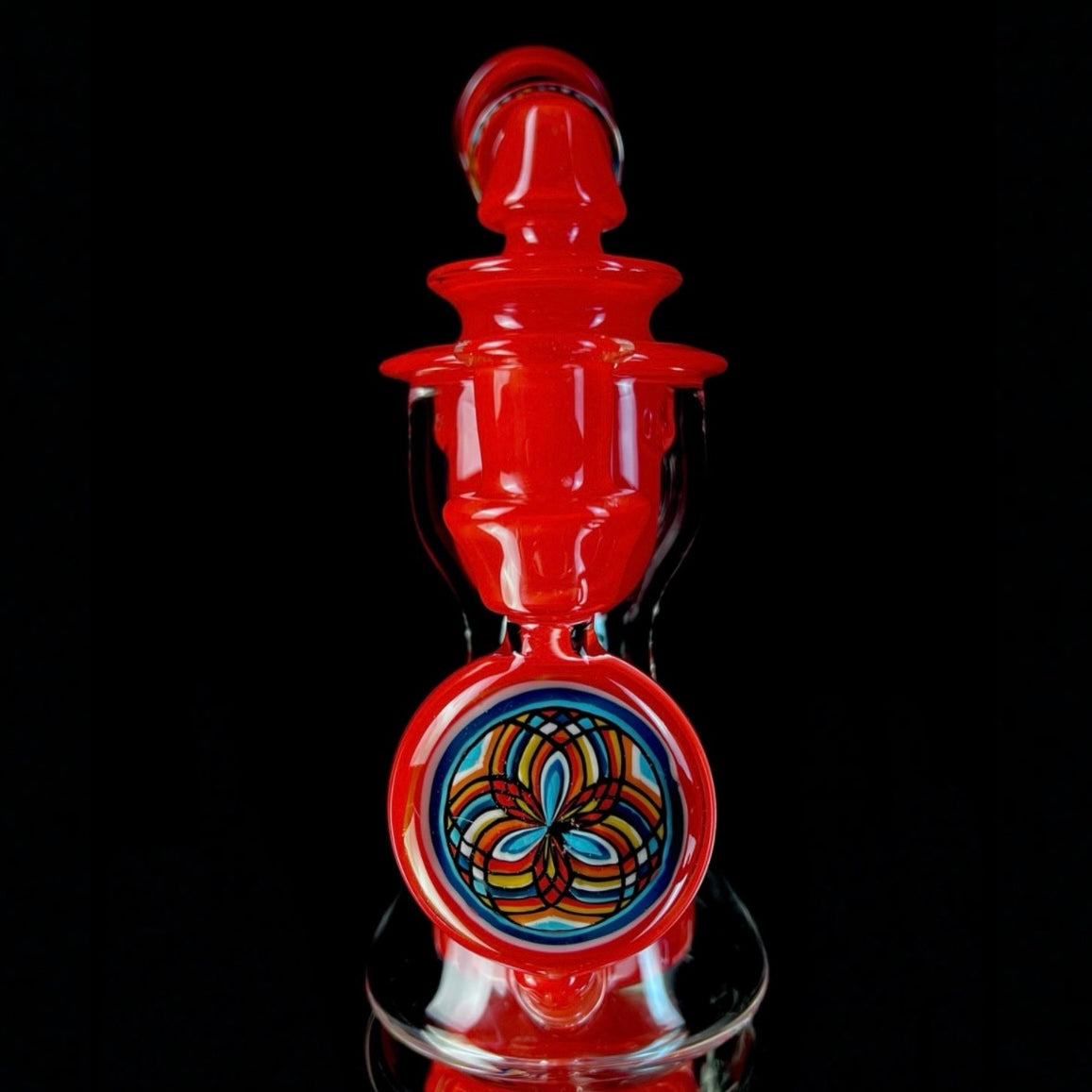 Red and clear glass smoking device with colorful designs on a white background.