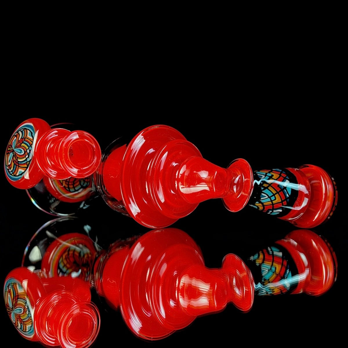 Red and clear glass smoking device with colorful designs on a white background.
