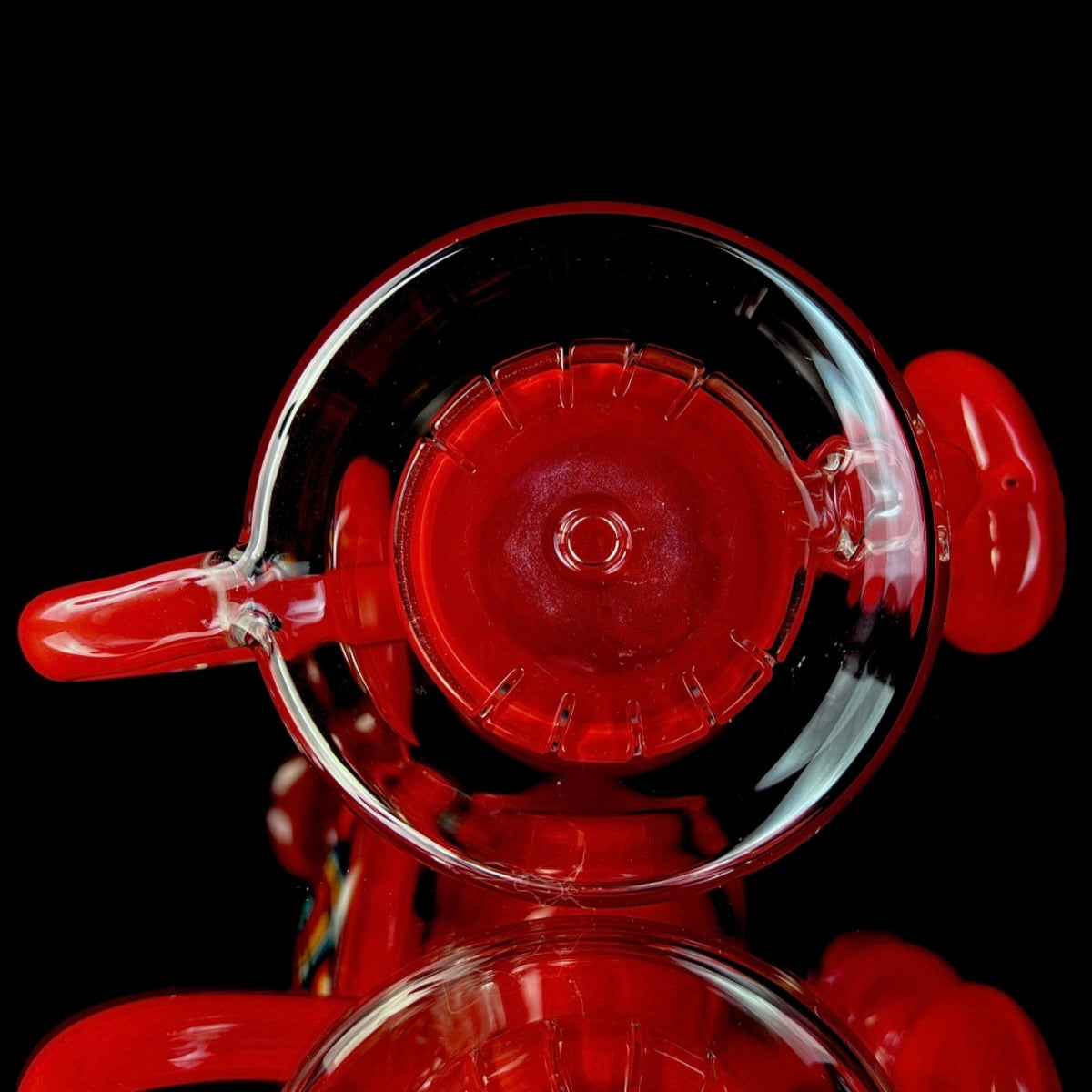 Red and clear glass smoking device with colorful designs on a white background.