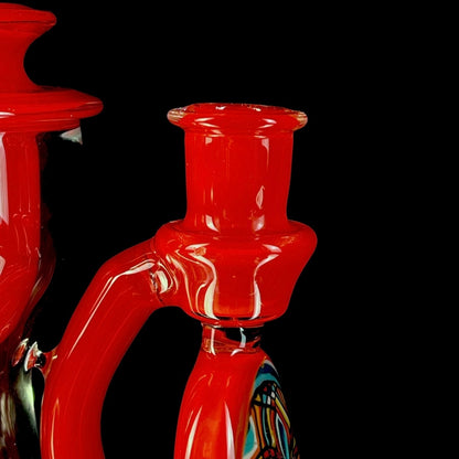 Red and clear glass smoking device with colorful designs on a white background.