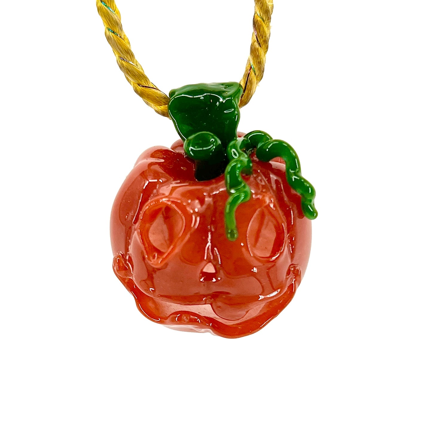 A glass pendant necklace with a orange and green pumpkin-shaped figure on a yellow cord.