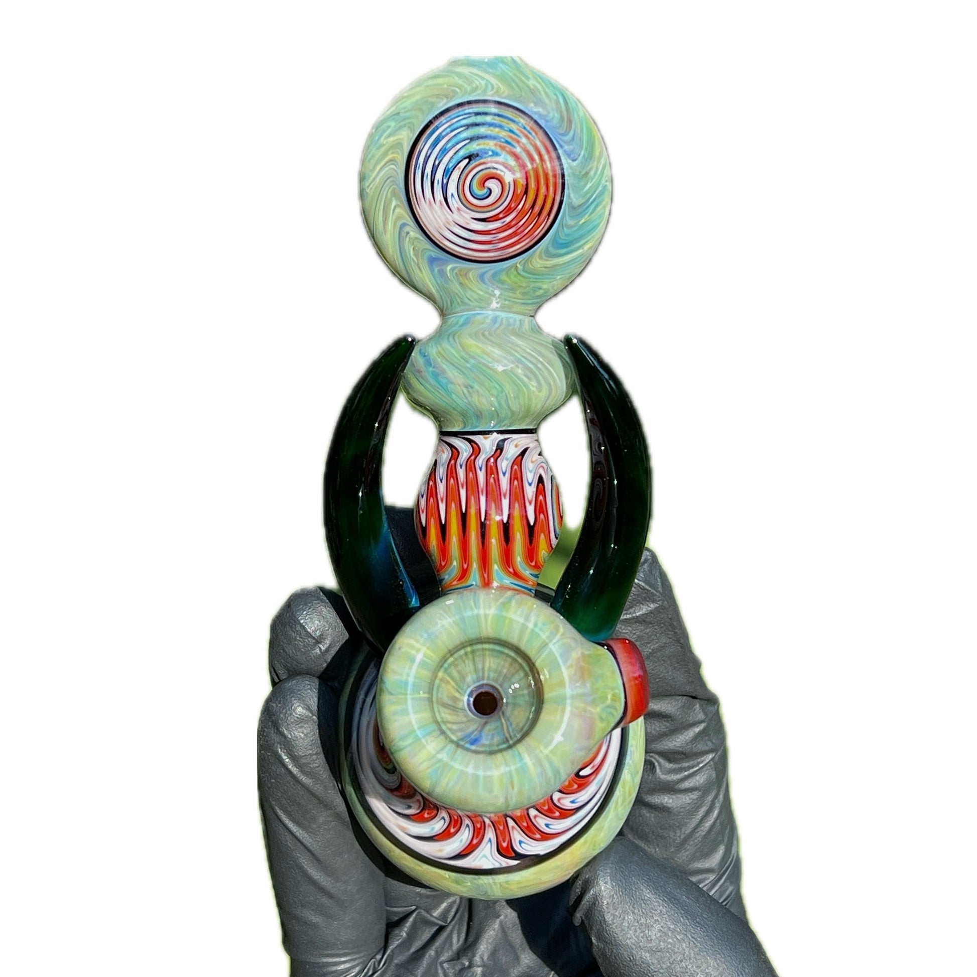 A hand holding a colorful glass hammer with a unique design, featuring predominantly green and red colors with black accents.