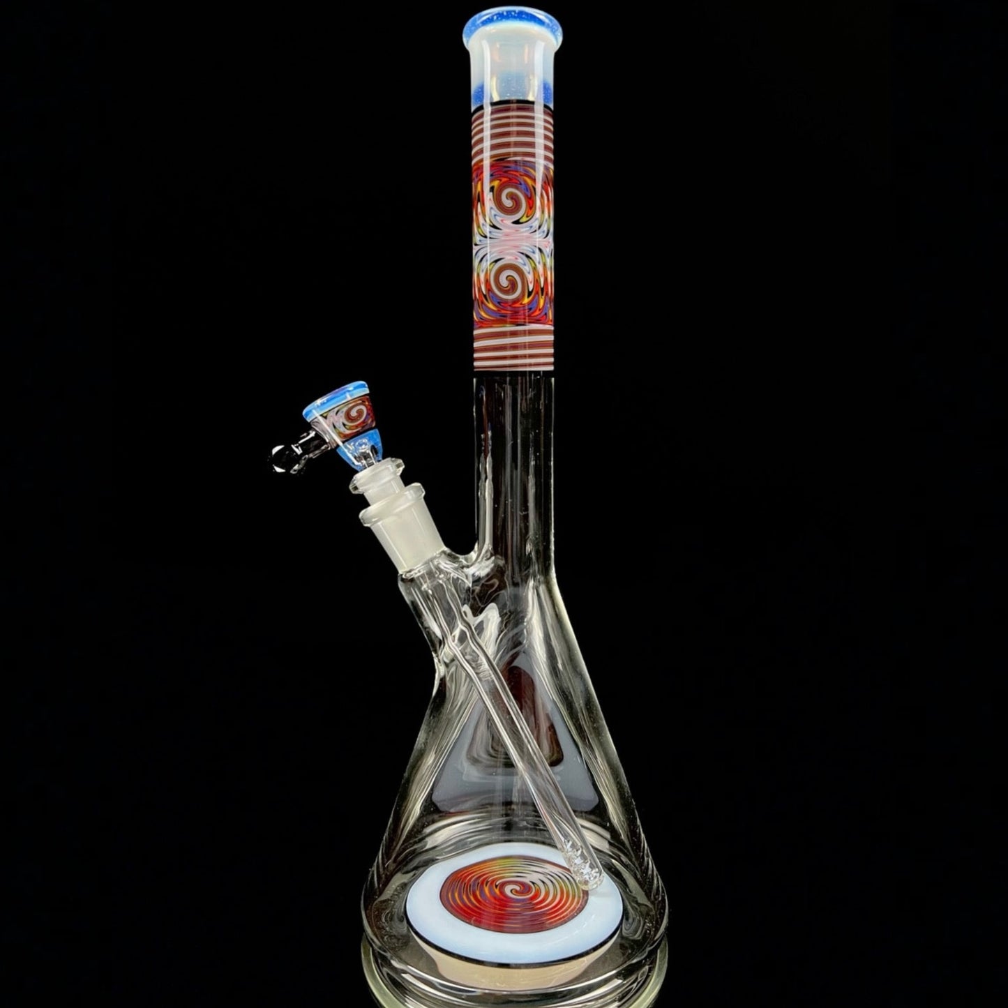 A tall, clear glass beaker with a colorful geometric pattern near the top, featuring a removable down stem and a 3-hole slide.