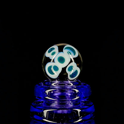 A multicolored glass marble with a design resembling a flower with blue petals on a white background, with a diameter approximately of 22mm.