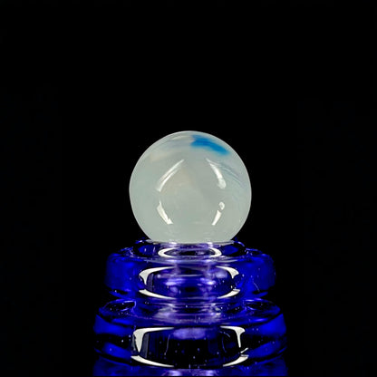 A multicolored glass marble with a design resembling a flower with blue petals on a white background, with a diameter approximately of 22mm.