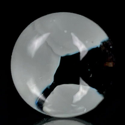 A multicolored glass marble with a design resembling a flower with blue petals on a white background, with a diameter approximately of 22mm.