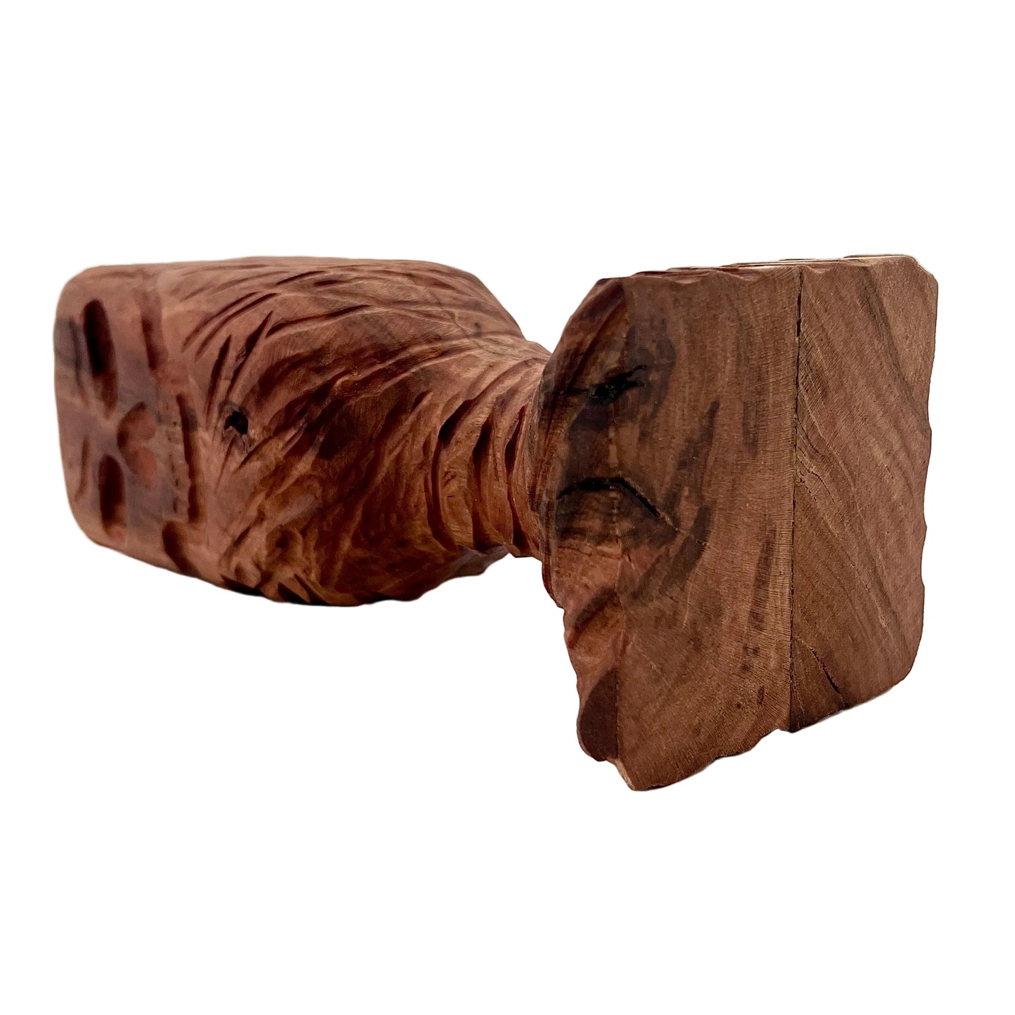 Wooden chalice with a skull carved into it placed on its side on a white background.