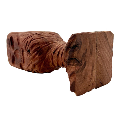 Wooden chalice with a skull carved into it placed on its side on a white background.